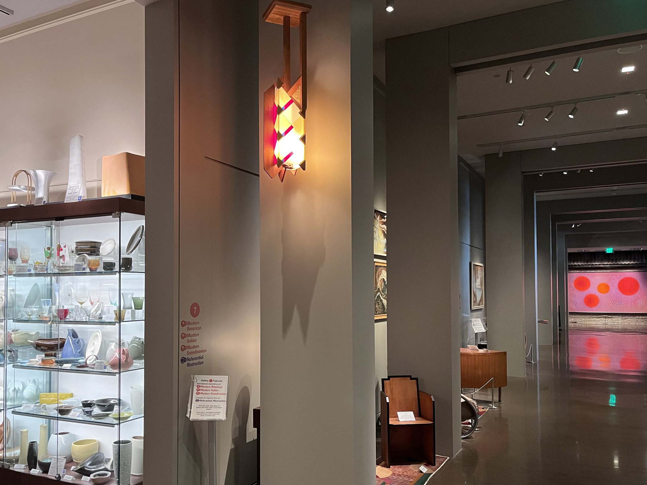 Kirkland Museum's Promenade Gallery with a geometric red, blue, cream and wood chandelier hanging in front of a column